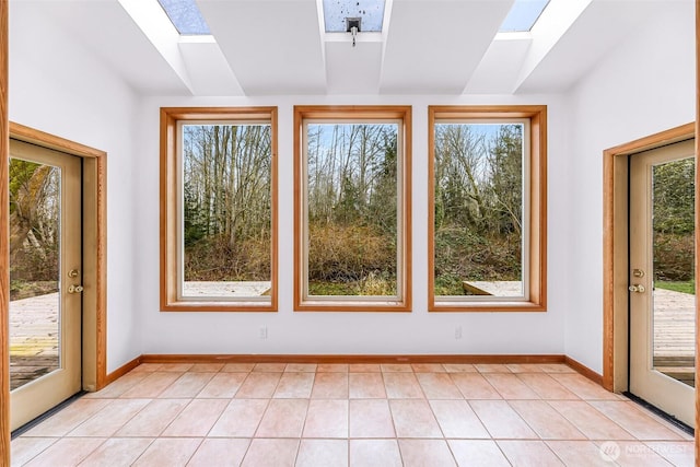 doorway with light tile patterned floors, baseboards, and a skylight