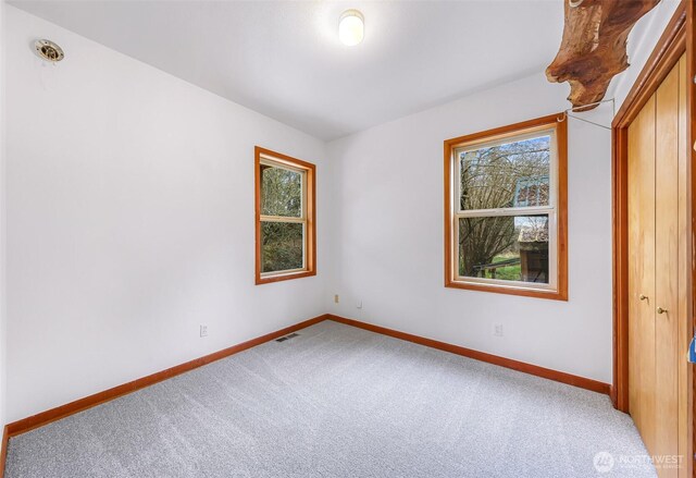 unfurnished bedroom with visible vents, light carpet, and baseboards