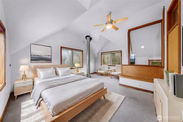 carpeted bedroom featuring a wood stove, baseboards, a ceiling fan, and vaulted ceiling