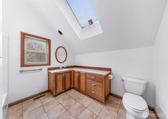 bathroom featuring visible vents, lofted ceiling with skylight, toilet, baseboards, and vanity