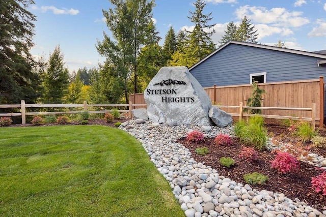 community / neighborhood sign featuring a yard and fence