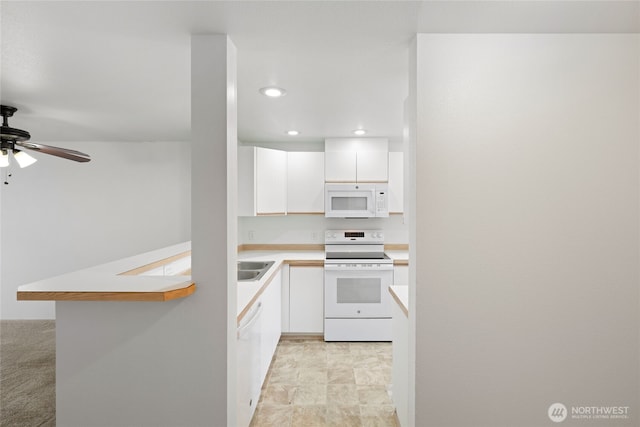 kitchen featuring light countertops, white appliances, white cabinetry, and recessed lighting