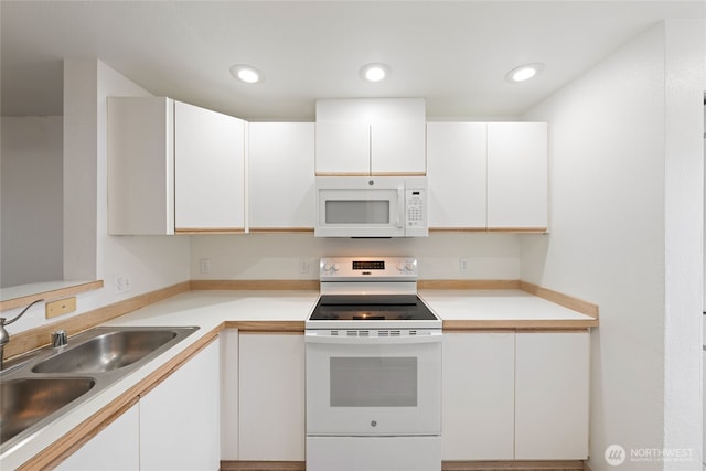 kitchen with light countertops, white appliances, a sink, and white cabinetry