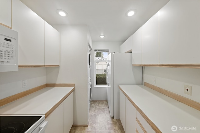 kitchen with white appliances, white cabinetry, light countertops, and recessed lighting