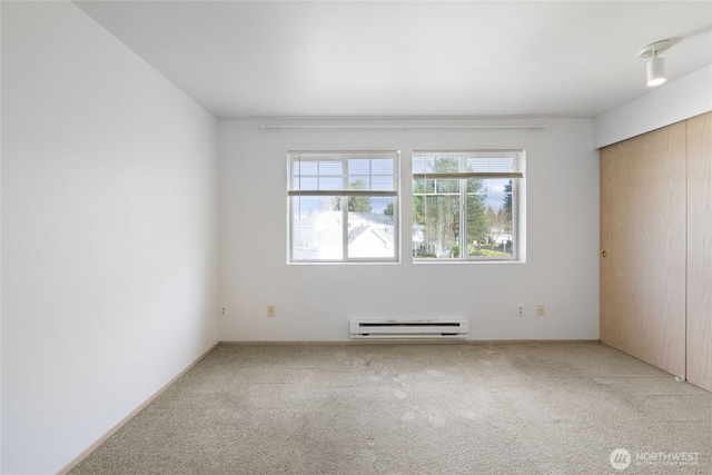 spare room with carpet and a baseboard heating unit