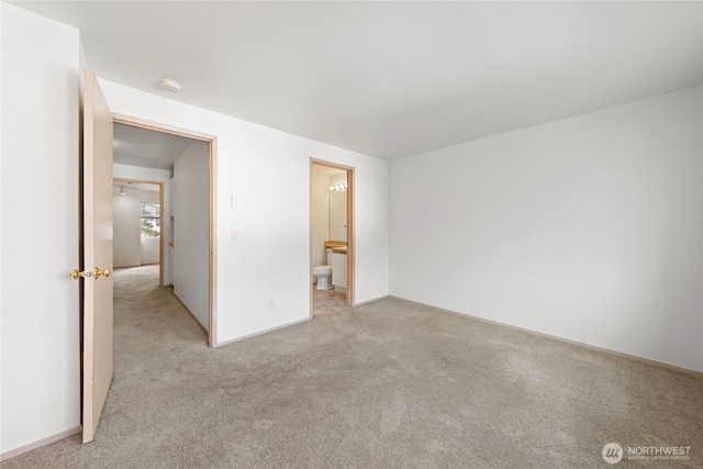 unfurnished bedroom featuring light carpet and ensuite bath