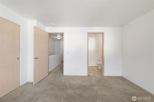 unfurnished bedroom with ensuite bath, baseboards, and carpet flooring