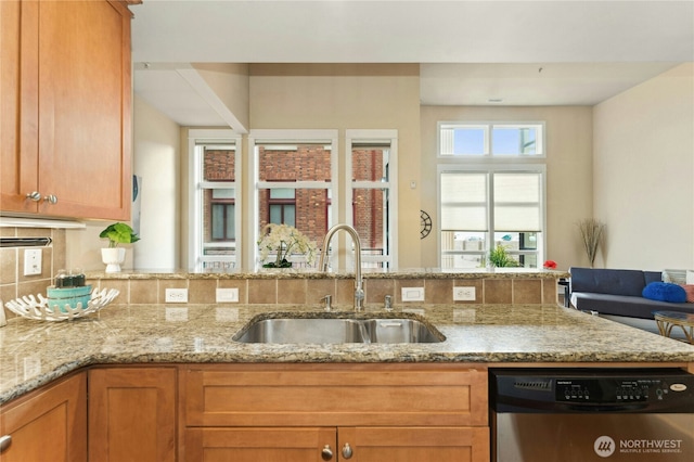 kitchen featuring stainless steel dishwasher, backsplash, a sink, and light stone countertops