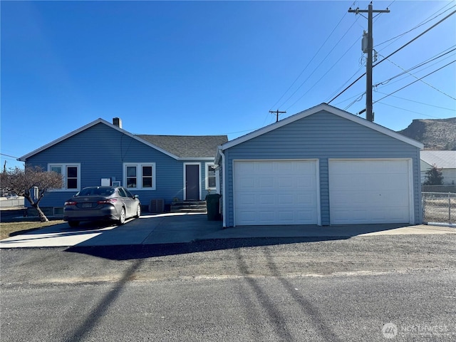 single story home featuring a detached garage and roof with shingles