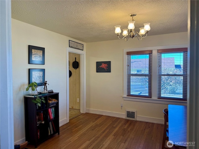 dining room featuring a chandelier, a textured ceiling, wood finished floors, visible vents, and baseboards