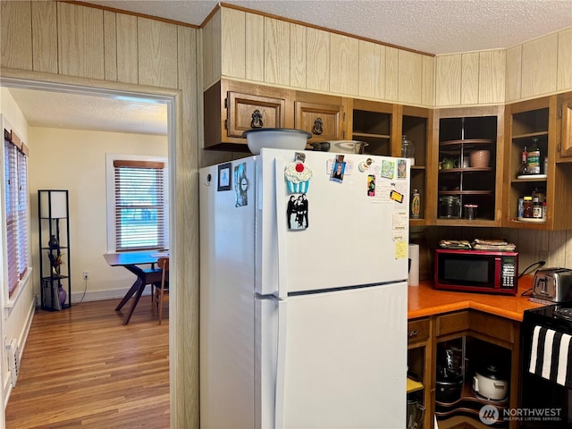 kitchen with a textured ceiling, light countertops, light wood-type flooring, and freestanding refrigerator