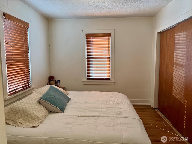 bedroom with a textured ceiling, baseboards, and wood finished floors