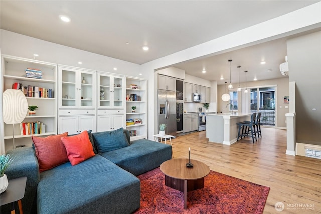 living area featuring light wood-style floors, recessed lighting, visible vents, and baseboards