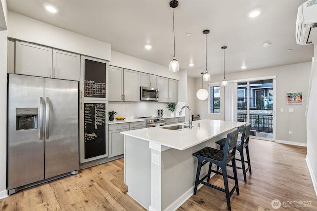 kitchen featuring an AC wall unit, appliances with stainless steel finishes, a sink, and gray cabinetry