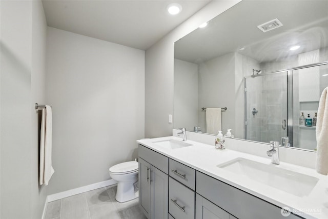 bathroom featuring toilet, a stall shower, a sink, and visible vents