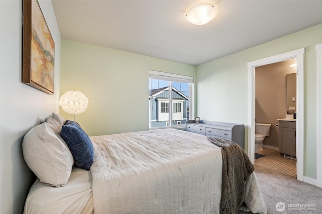 carpeted bedroom with ensuite bath and baseboards