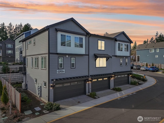 multi unit property featuring a residential view, fence, and an attached garage