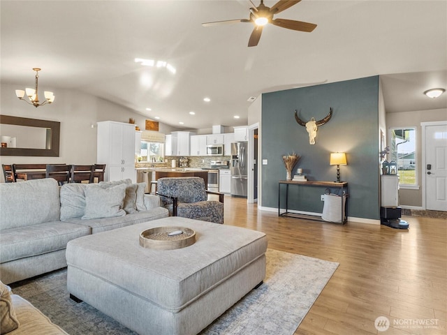 living area featuring lofted ceiling, light wood-type flooring, plenty of natural light, and recessed lighting