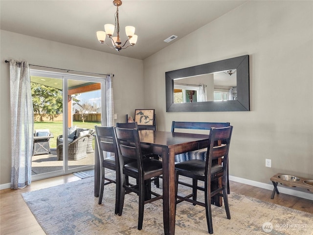 dining area with baseboards, visible vents, a chandelier, and wood finished floors