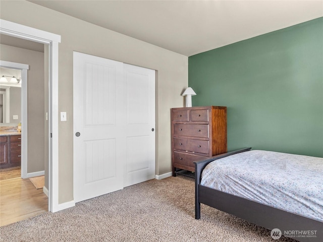 bedroom with a closet, light carpet, and baseboards