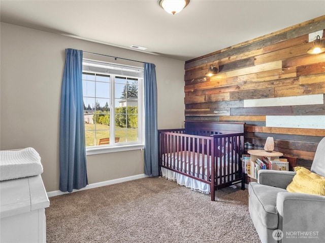 bedroom with carpet floors, wood walls, visible vents, and baseboards