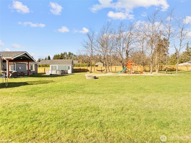 view of yard with a trampoline, an outbuilding, a playground, and a fenced backyard