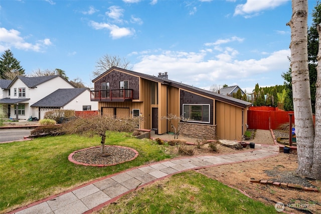 mid-century modern home with a chimney, board and batten siding, a front yard, a balcony, and stone siding