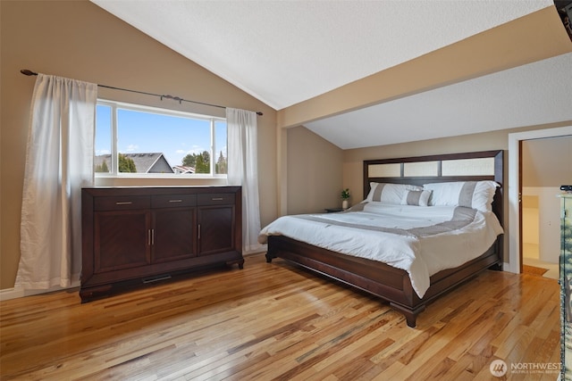 bedroom with lofted ceiling and light wood-style floors