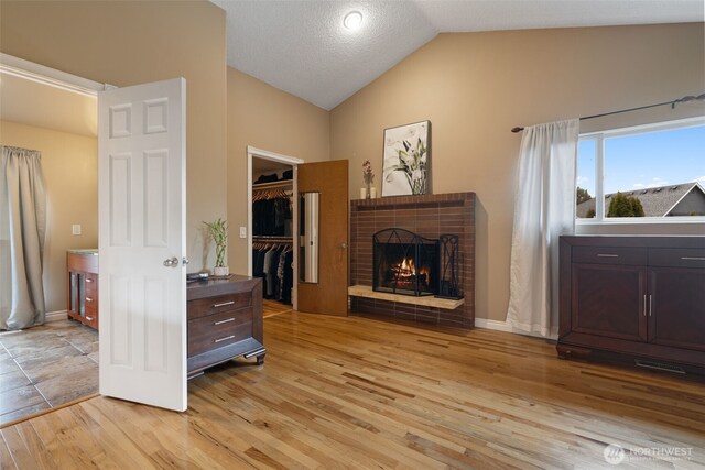 living area featuring lofted ceiling, visible vents, a fireplace, and light wood finished floors