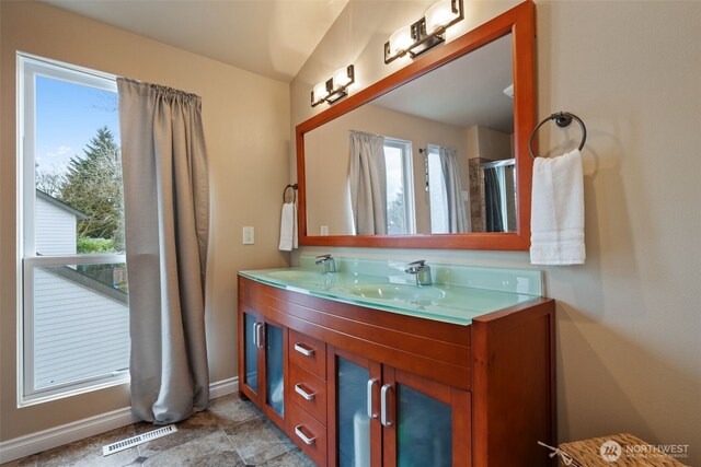 bathroom with visible vents, a sink, baseboards, and double vanity