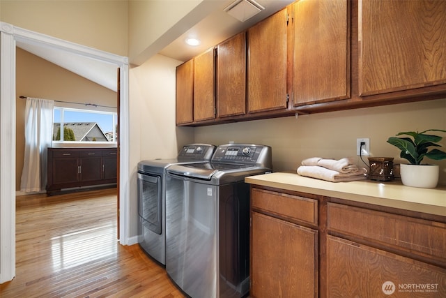 laundry room with visible vents, separate washer and dryer, light wood-type flooring, and cabinet space