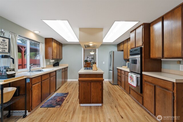 kitchen featuring stainless steel appliances, a center island, light countertops, and light wood-style flooring