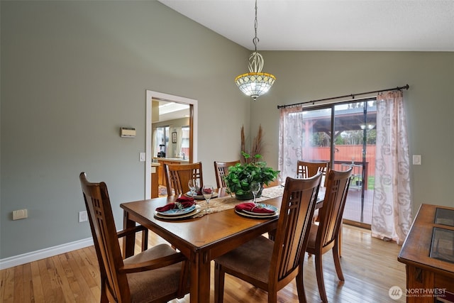 dining space featuring lofted ceiling, light wood finished floors, and baseboards