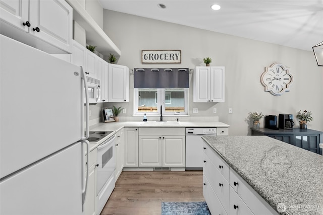 kitchen featuring white appliances, white cabinets, light wood-style floors, and a sink