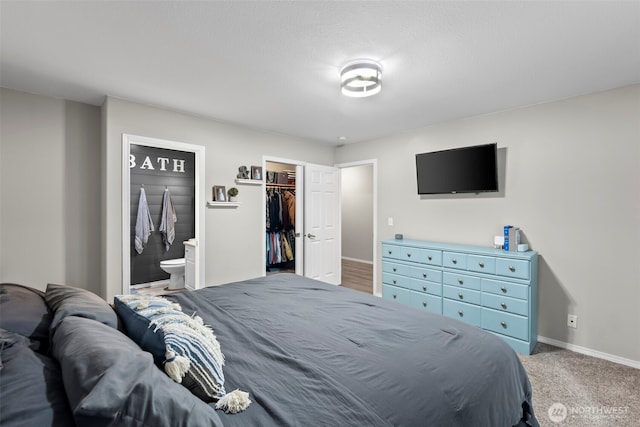 bedroom with a walk in closet, ensuite bathroom, a closet, carpet, and baseboards