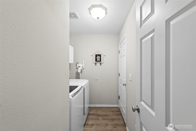 laundry area with visible vents, baseboards, dark wood finished floors, cabinet space, and separate washer and dryer