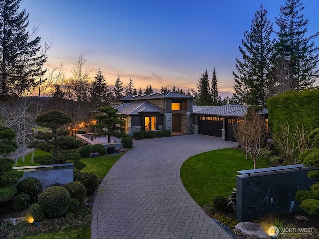 view of front of home featuring a front yard, a standing seam roof, a garage, decorative driveway, and metal roof