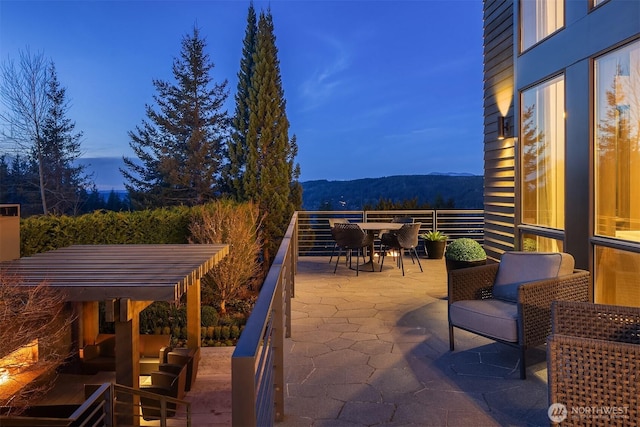 patio terrace at dusk with an outdoor living space, outdoor dining area, and a balcony