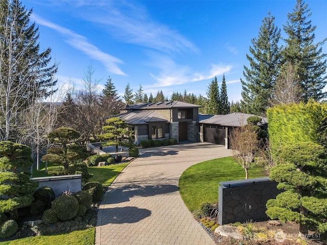 view of front of home featuring decorative driveway, metal roof, an attached garage, and a standing seam roof