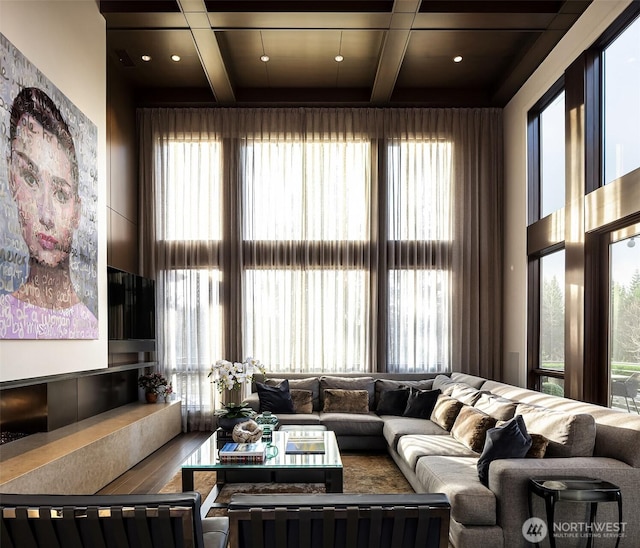 living area with beam ceiling, a high ceiling, and coffered ceiling