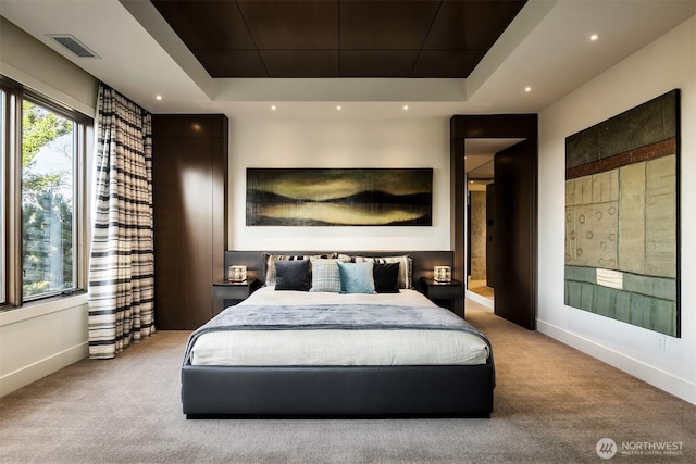 bedroom with visible vents, baseboards, a tray ceiling, and carpet