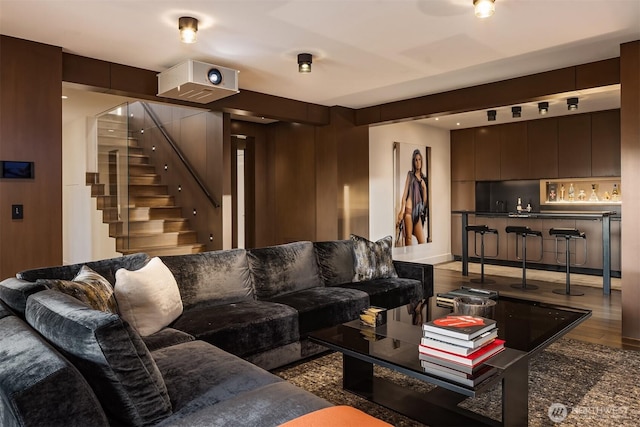 living room with stairway, a bar, and wood finished floors