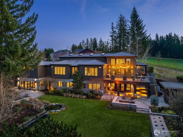 back of property with stairs, a lawn, a patio, metal roof, and a standing seam roof