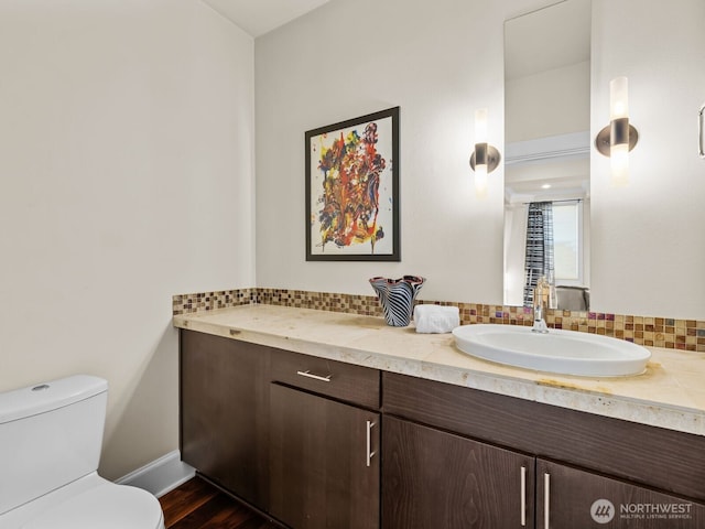 bathroom with toilet, baseboards, decorative backsplash, and vanity