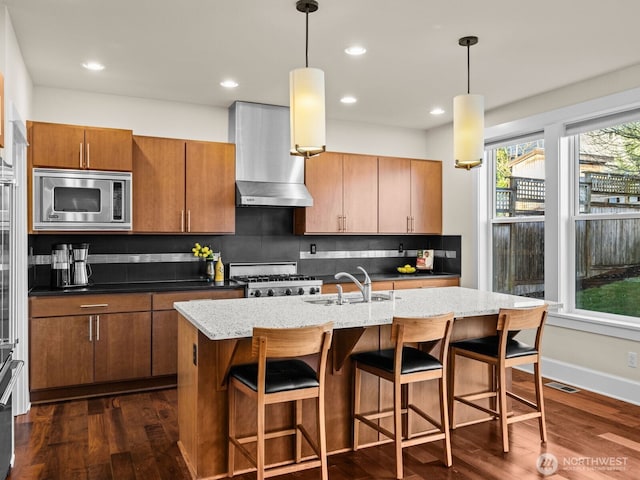 kitchen with visible vents, range, wall chimney exhaust hood, stainless steel microwave, and a sink