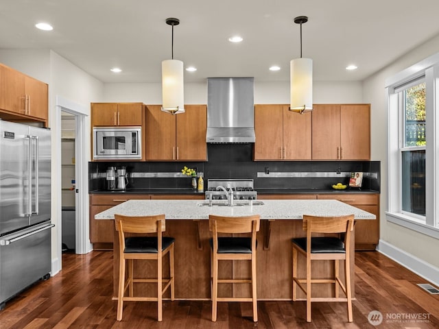 kitchen featuring stainless steel appliances, a sink, visible vents, wall chimney range hood, and backsplash