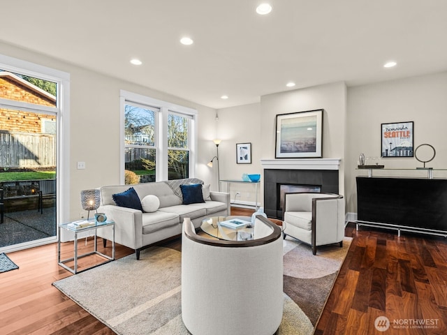 living room with wood finished floors, a tile fireplace, and recessed lighting