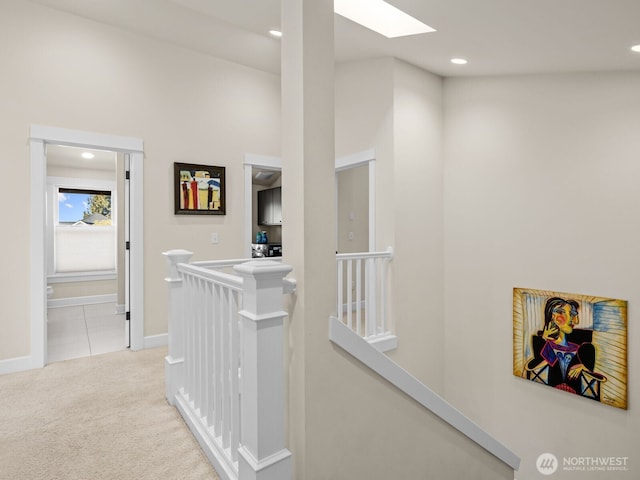 hall with a skylight, recessed lighting, carpet flooring, and an upstairs landing