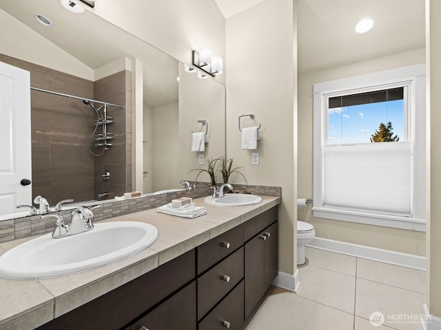 bathroom featuring tile patterned flooring, tiled shower, a sink, and toilet