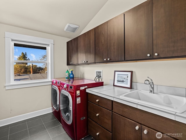 washroom featuring cabinet space, baseboards, independent washer and dryer, dark tile patterned floors, and a sink